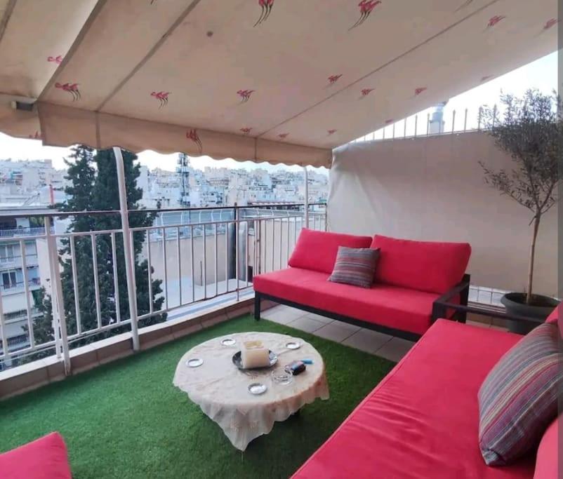 ein Wohnzimmer mit einem roten Sofa und einem Tisch in der Unterkunft 7th floor spacious veranda in the heart of Athens in Athen