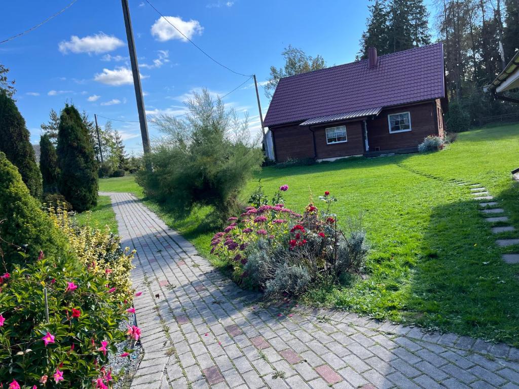 a brick path in front of a house with flowers at Rojaus kampelis. Kaimo turizmas in Gudžiūnai