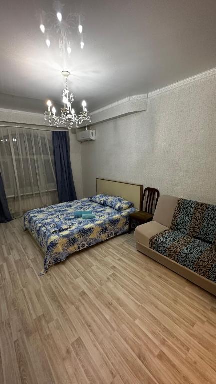 a bedroom with two beds and a chandelier at Однокомнатная квартира in Aktobe