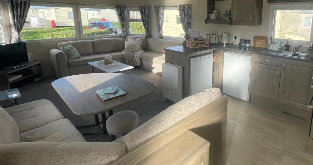 eine Küche und ein Wohnzimmer mit einem Sofa und einem Tisch in der Unterkunft Trecco Bay Porthcawl Caravan 8 berth PALMS 4 in Newton