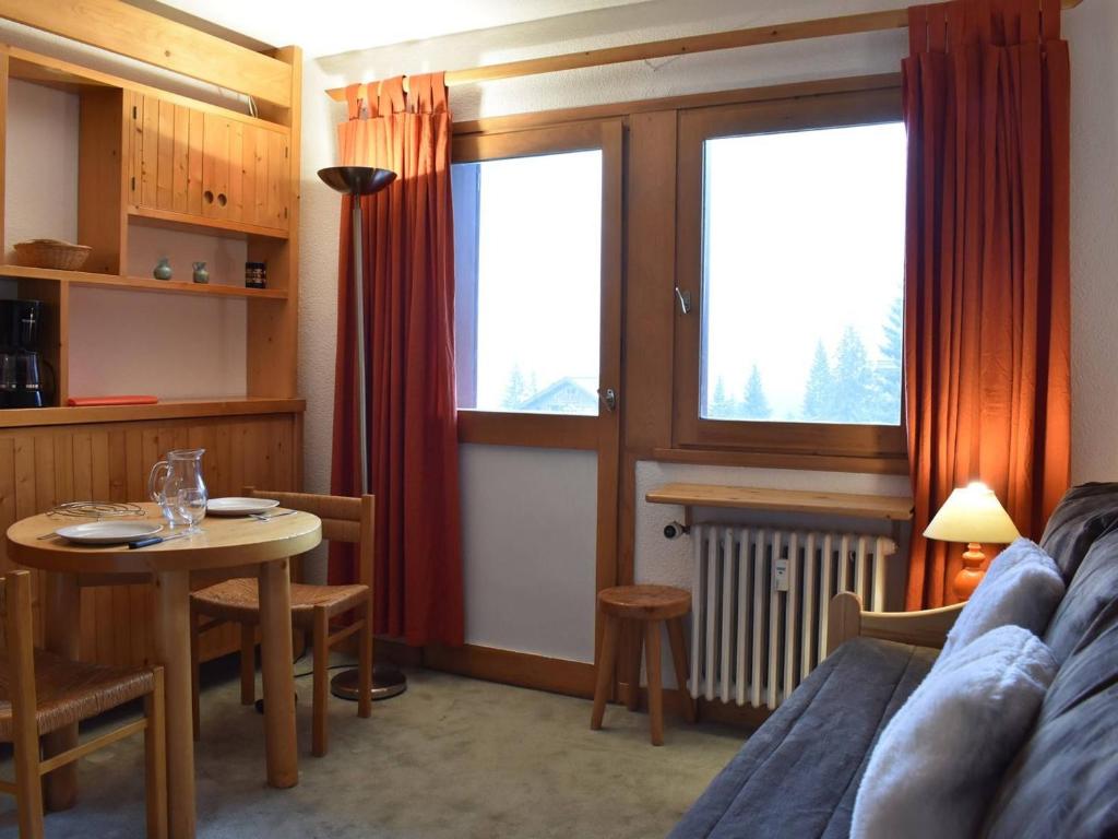 - un salon avec un canapé, une table et des fenêtres dans l'établissement Studio cosy à Meribel, aux pieds des pistes, proche des commerces et restaurants, pour 2 personnes - FR-1-180-542, à Les Allues