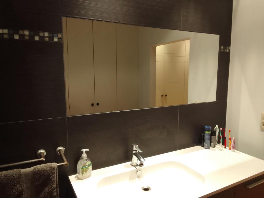 uma casa de banho com um lavatório branco e um espelho. em Superbe appartement em Antuérpia