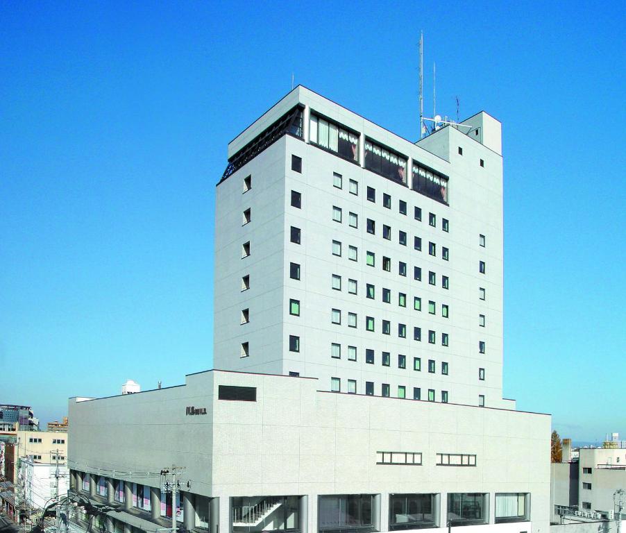 un grand bâtiment blanc avec des fenêtres au-dessus dans l'établissement Hirosaki Park Hotel, à Hirosaki