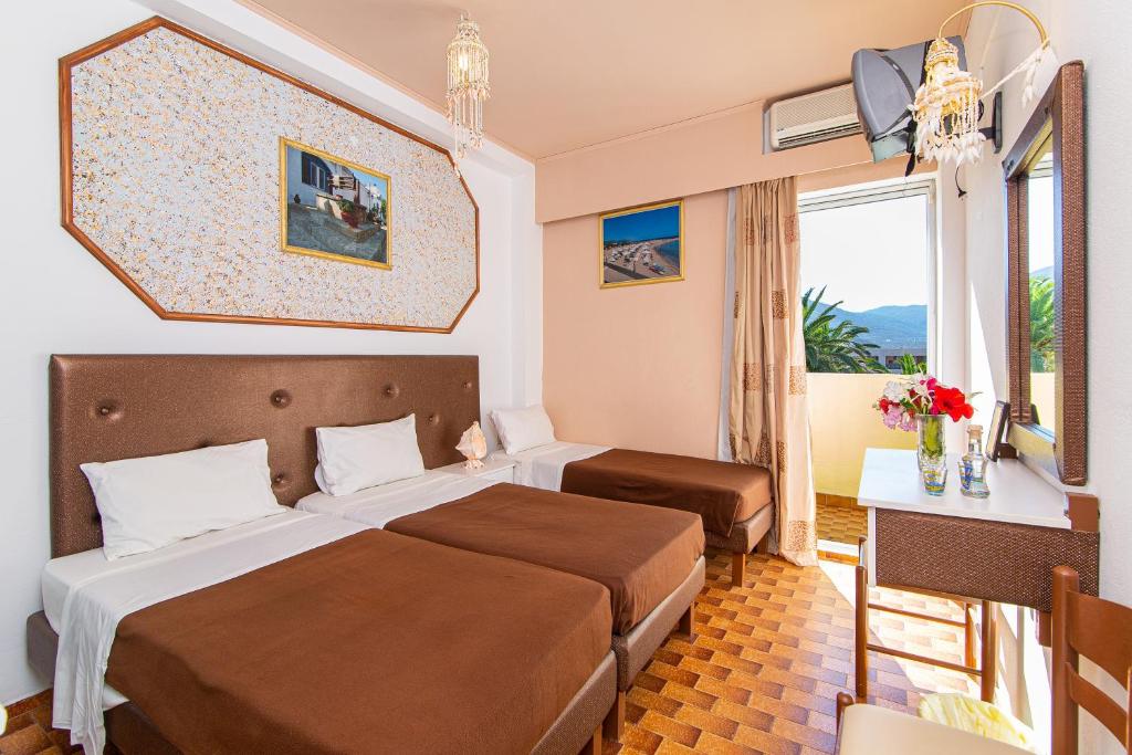 um quarto de hotel com uma cama, uma secretária e uma janela em Minoa Hotel em Malia