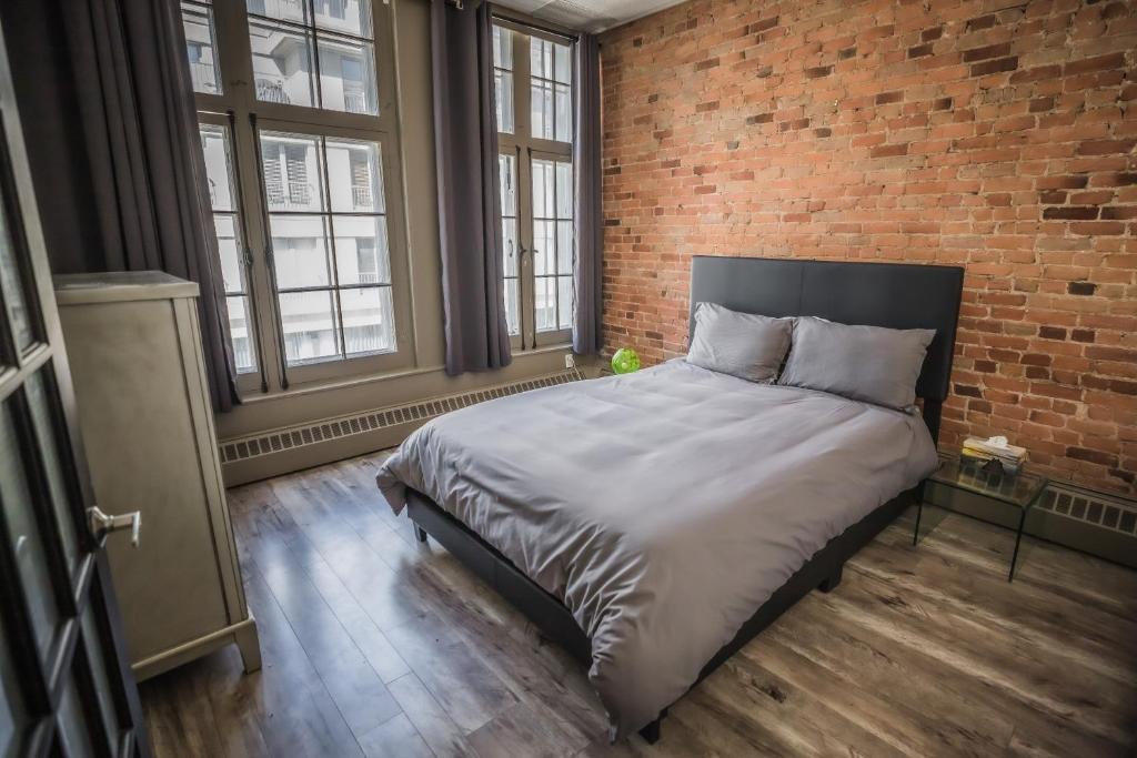 1 dormitorio con 1 cama grande y pared de ladrillo en Le 402 en Montreal