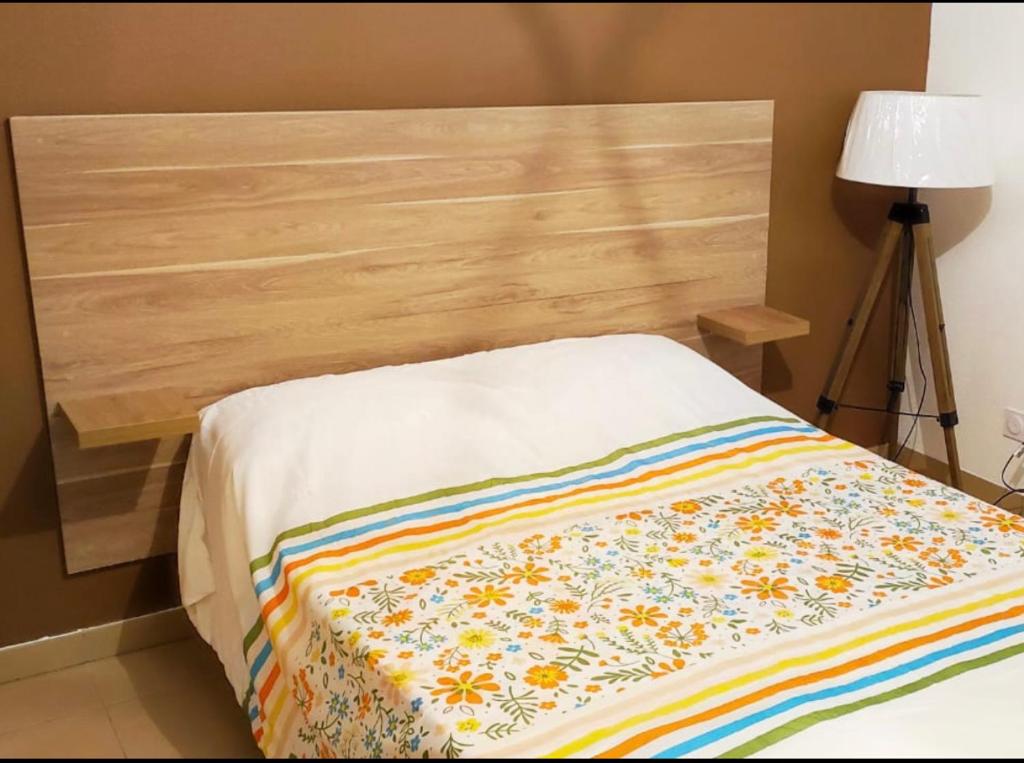- un lit avec une tête de lit en bois et une couverture colorée dans l'établissement Les docks libres sud, à Marseille