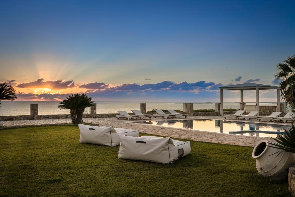 a resort yard with chairs and a pool and the ocean at Agnanti Suites in Minia