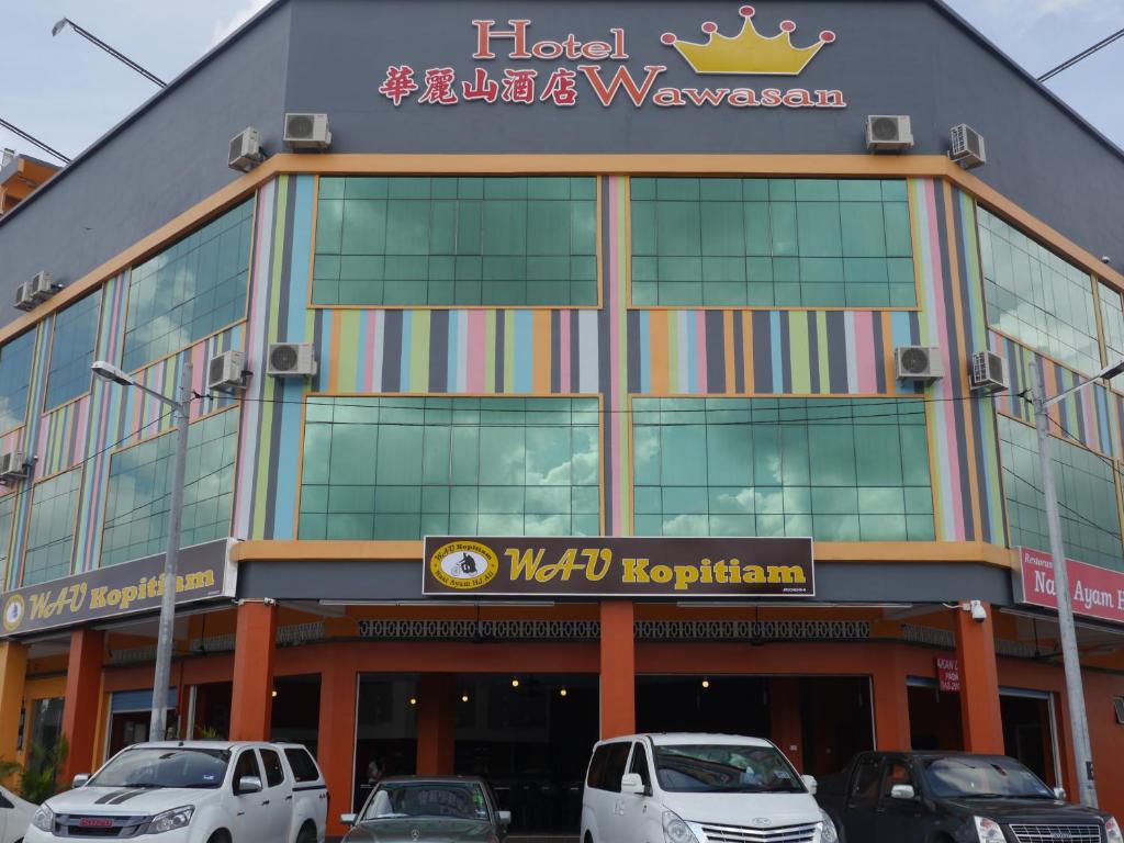 a hotel with cars parked in front of it at Hotel Wawasan in Simpang Renggam