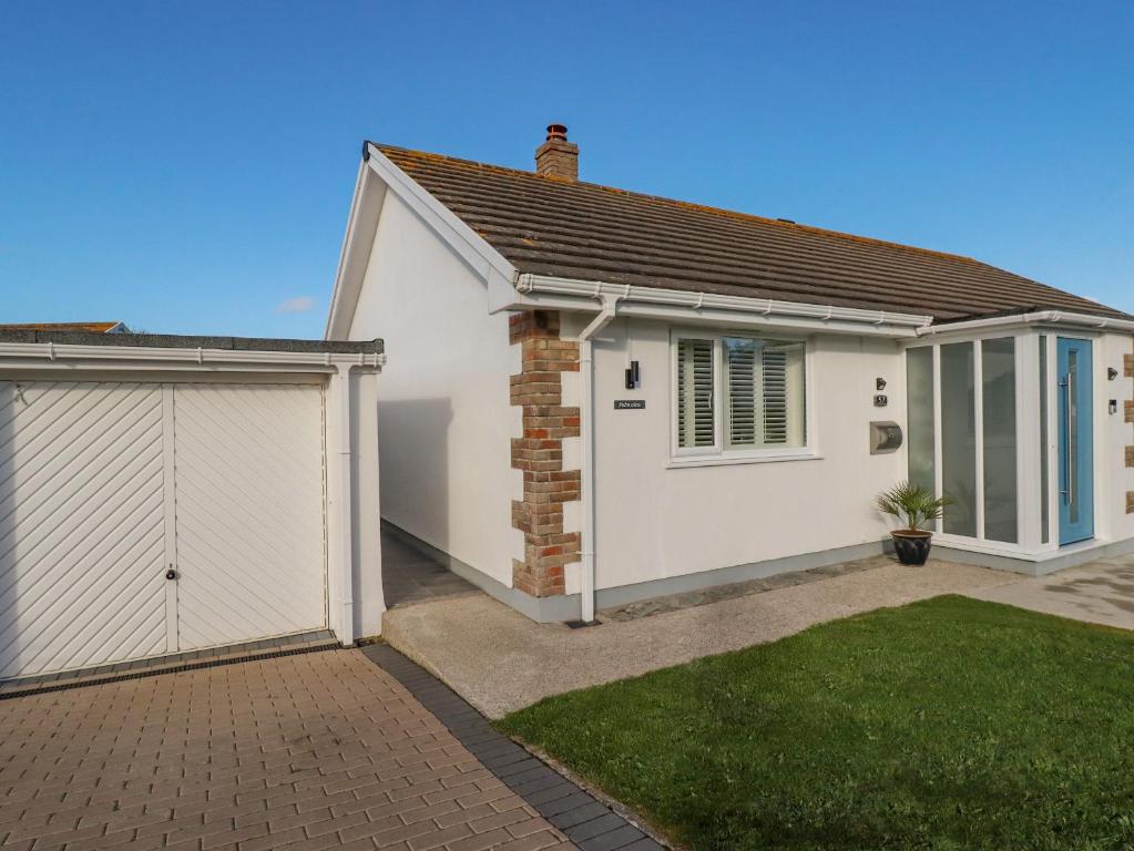 uma casa branca com garagem e relvado em Palm View em Newquay