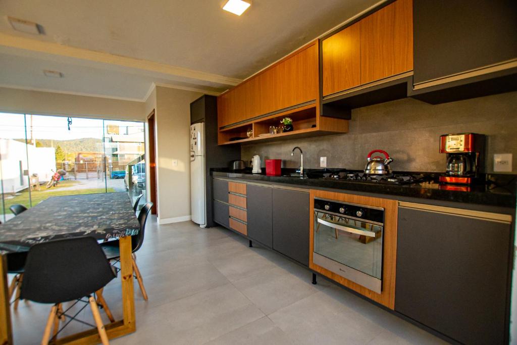 Una cocina con gabinetes de madera y una mesa en ella. en Lake View Guest House, en Praia do Rosa