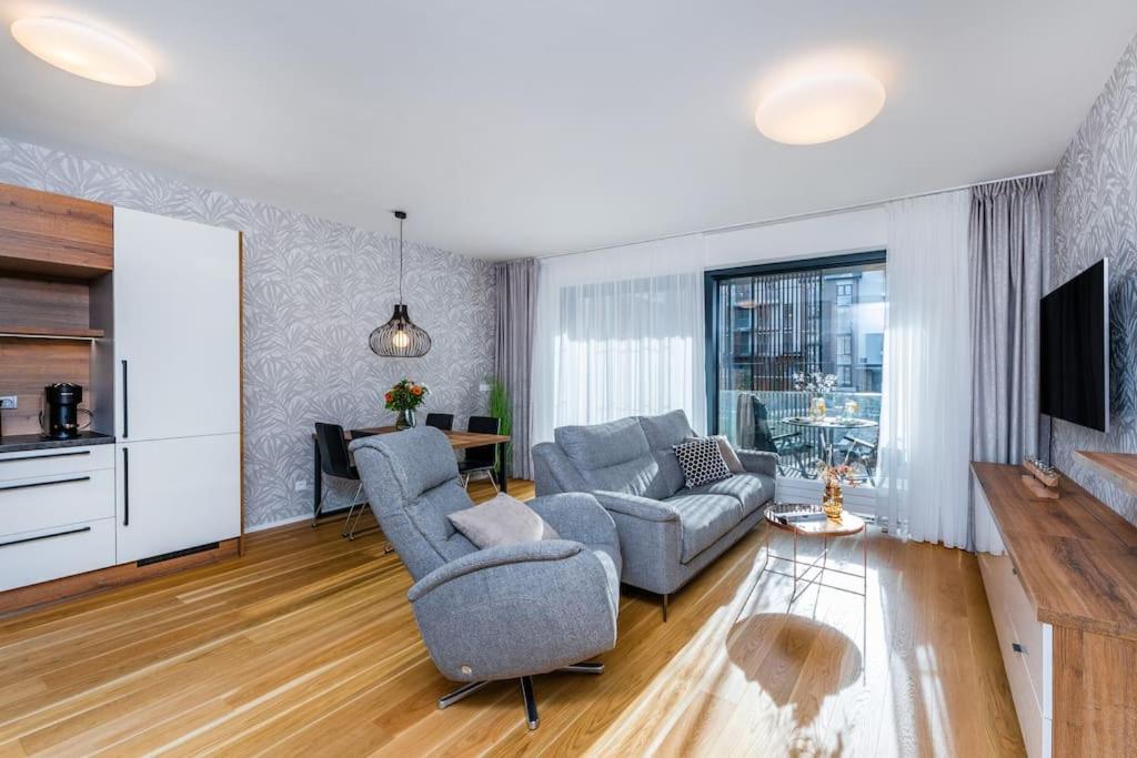 een woonkamer met 2 stoelen, een bank en een tv bij Apartament I313 Molo Lipno with private wellness in Lipno nad Vltavou