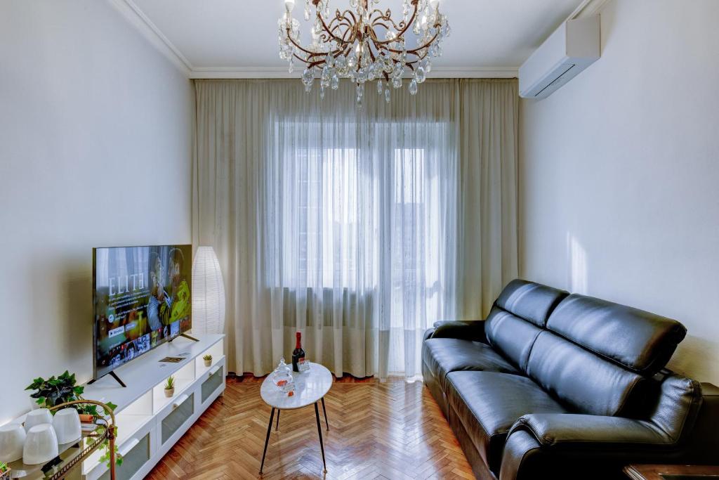 uma sala de estar com um sofá de couro e uma televisão em Bramante House - Intero Trilocale vicino alla Metro em Turim