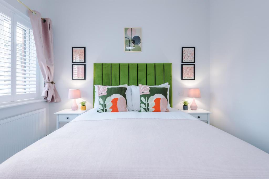 1 dormitorio con 1 cama blanca grande y cabecero verde en Beechwood Lodge Serviced Apartment, en Coventry