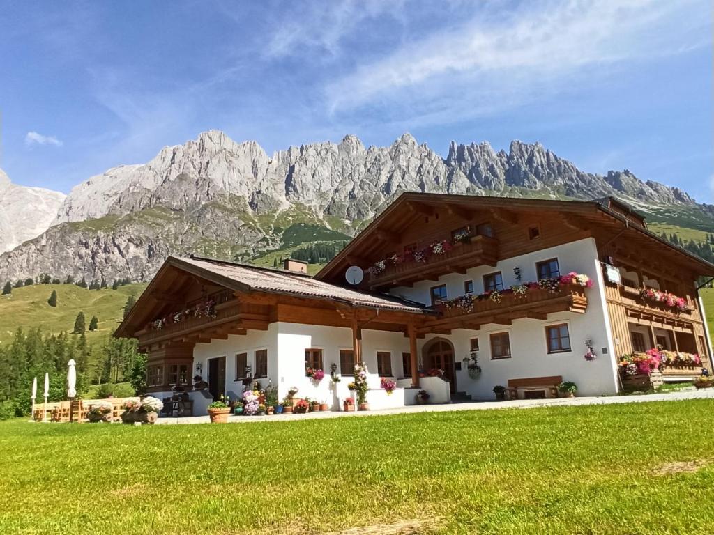 a house in the mountains with a green lawn at Gästehaus Gschwandtner in Mühlbach am Hochkönig