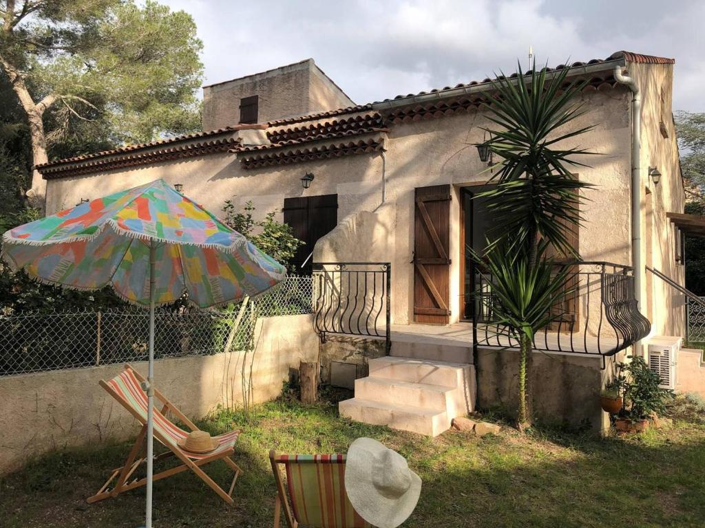 une maison avec une chaise et un parasol dans la cour dans l'établissement Studio Mezzanine avec Jardin Privatif, Parking et Clim - Saint-Raphaël - FR-1-226A-81, à Saint-Raphaël