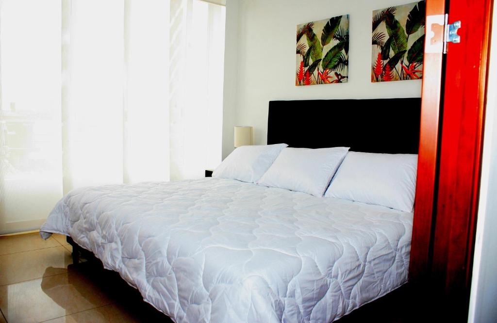 1 dormitorio con 1 cama blanca grande con sábanas blancas en Apartasuites AAA Modelia Bogotá, en Bogotá