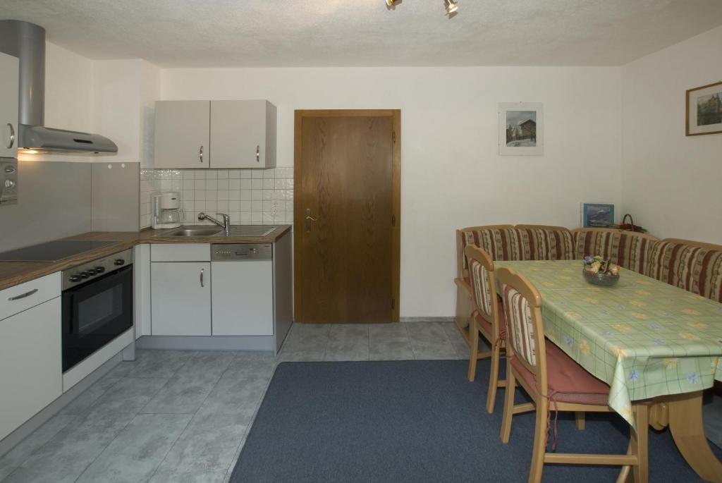 eine Küche mit einem Tisch und Stühlen sowie eine Küche mit weißen Schränken in der Unterkunft Haus Deiser in Kappl