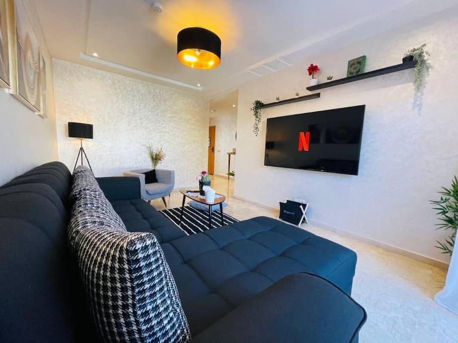 uma sala de estar com um sofá azul e uma televisão em A 2 minutes de Casa Finance City, appartement avec 2 Chambres em Casablanca
