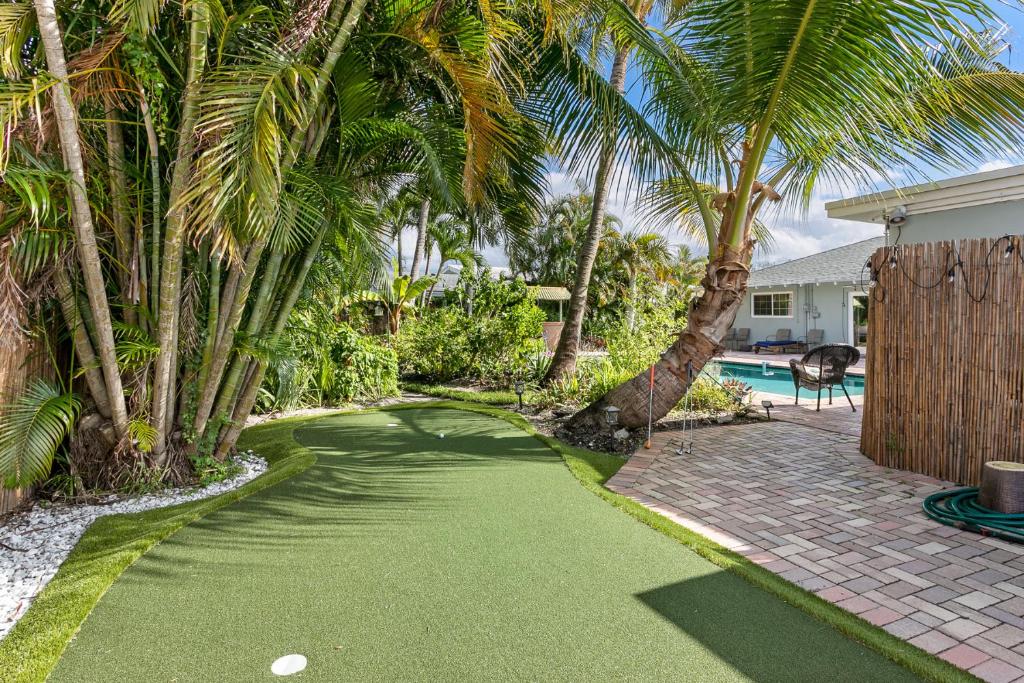 ein Putting Green mit Palmen und einem Pool in der Unterkunft Tropical Oasis - Heated Pool - 4 BE/2BA- 8 beds in North Palm Beach