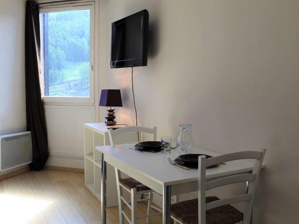 a dining room table with two chairs and a tv on the wall at Appartement Vars, 1 pièce, 2 personnes - FR-1-330B-149 in Vars