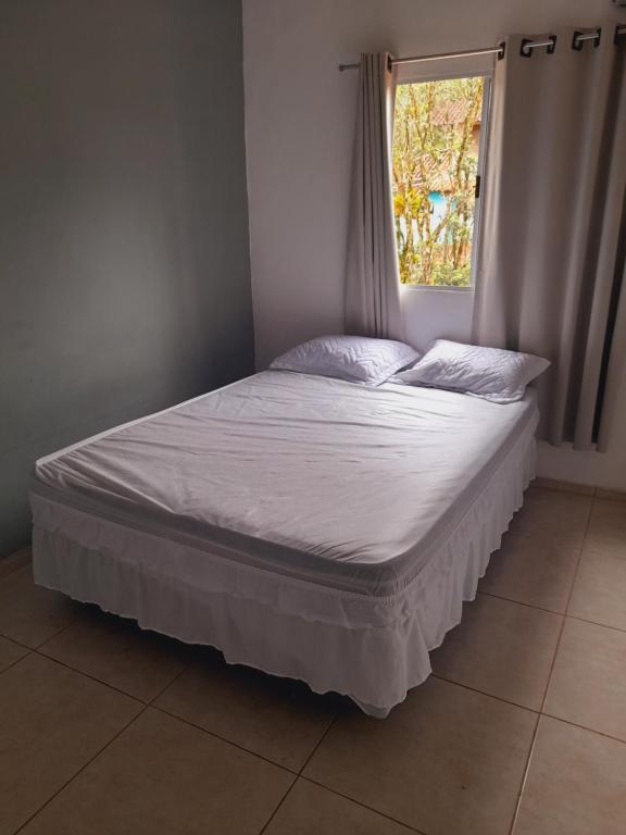 a bed in a room with a window at Lindo Flat em Maresias in São Sebastião