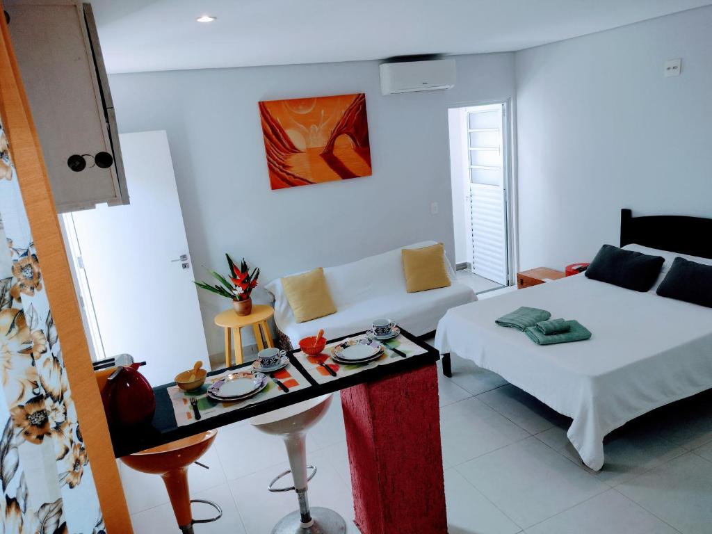 Habitación con cama, sofá y mesa. en Flat Ideal Guarujá - Apto Studio Mobiliado, Ar-Condic e Cozinha Completa, en Guarujá
