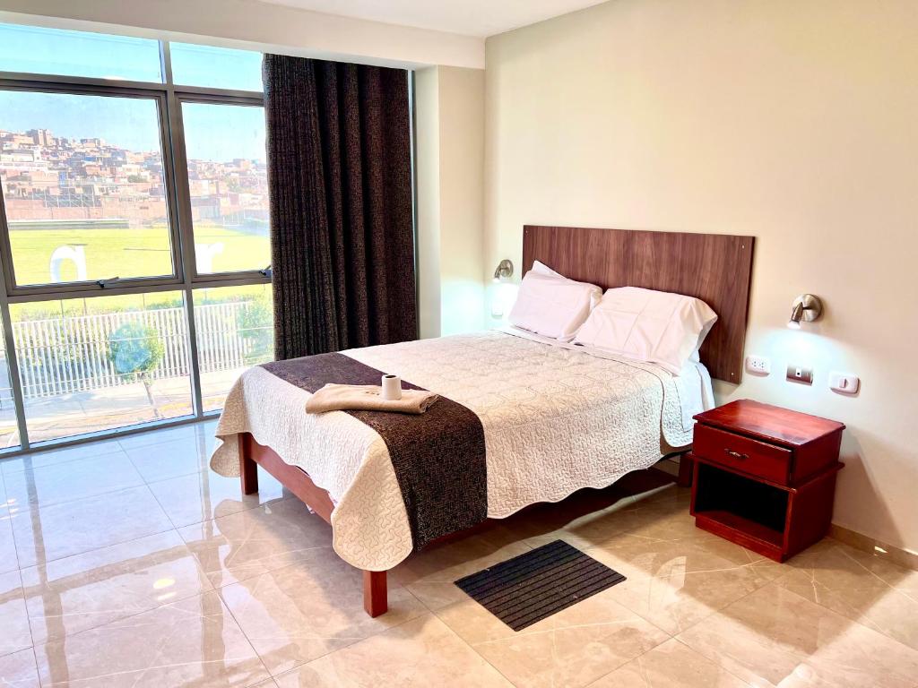 um quarto com uma cama e uma grande janela em HOTEL DORADO AREQUIPA em La Apacheta