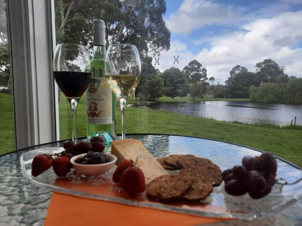 une table en verre avec une assiette de nourriture et un verre de vin dans l'établissement Abbivale Farm Cottage, à Harewood