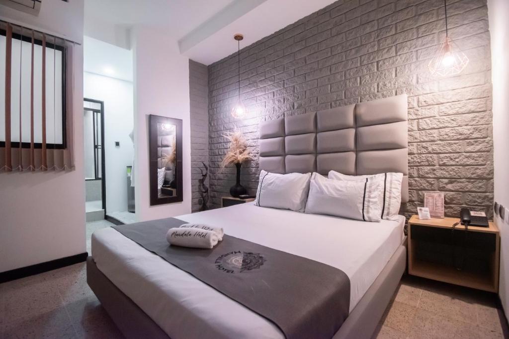 ein Schlafzimmer mit einem großen Bett mit Ziegelwand in der Unterkunft Mándala Hotel Belén in Medellín