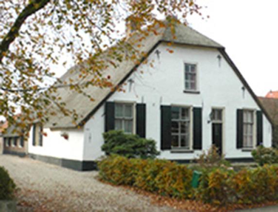 a white house with black windows and a tree at Paul en Lettie's Bed and Breakfast in Westbroek