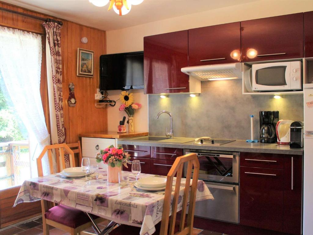 una cucina con tavolo, sedie e forno a microonde di Appartement Vars, 1 pièce, 3 personnes - FR-1-330B-127 a Vars