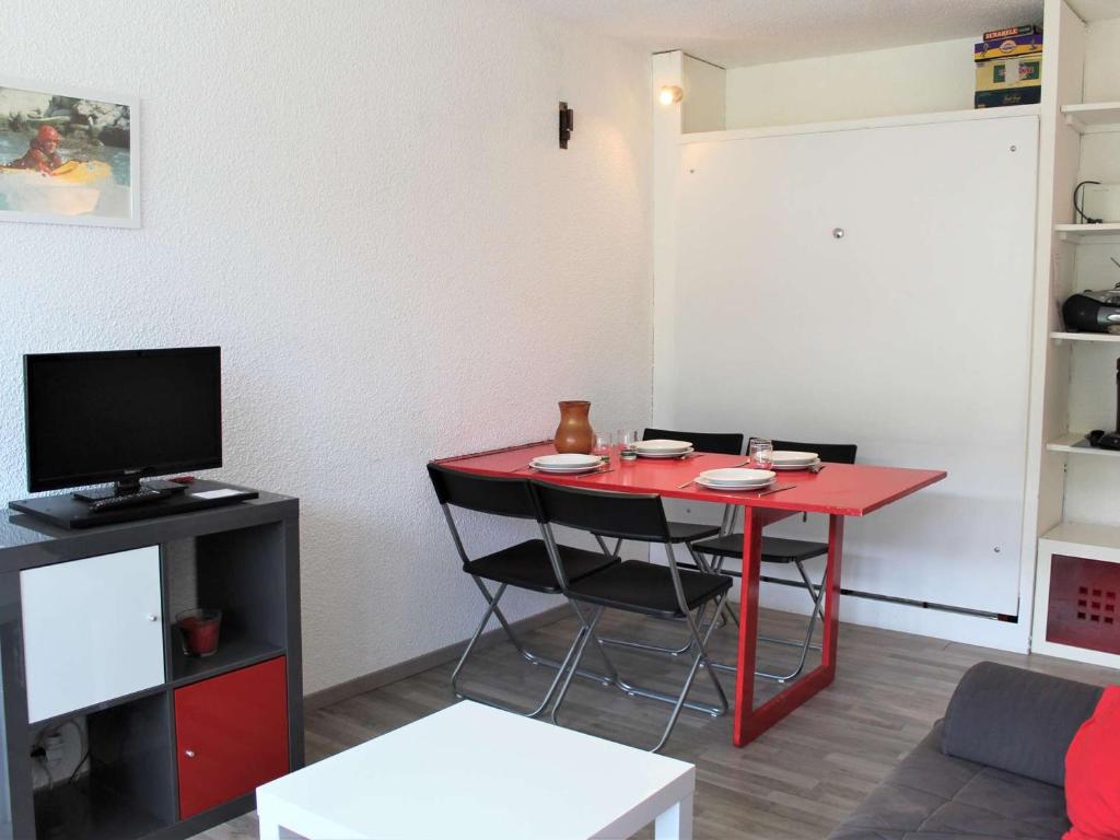 Cette chambre dispose d'une table rouge avec des chaises et d'une télévision. dans l'établissement Appartement idéal pour 4 à Vars, proche pistes et commerces, parking inclus - FR-1-330B-94, à Vars