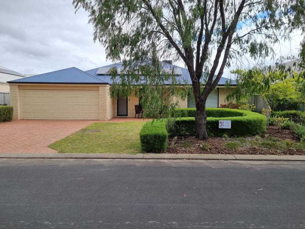 a house with a tree on the side of a street at Busselton Broadwater Holiday Home in Busselton