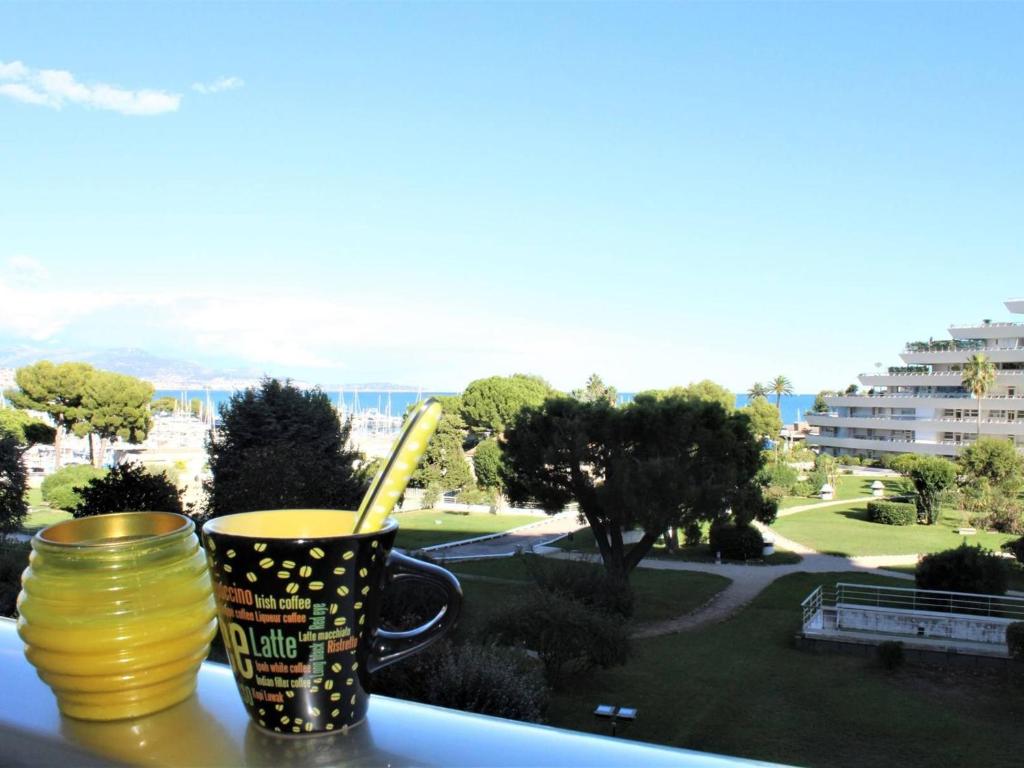 2 tazas en el alféizar de la ventana con vistas a un parque en Appartement Villeneuve-Loubet, 2 pièces, 4 personnes - FR-1-252A-9, en Villeneuve-Loubet
