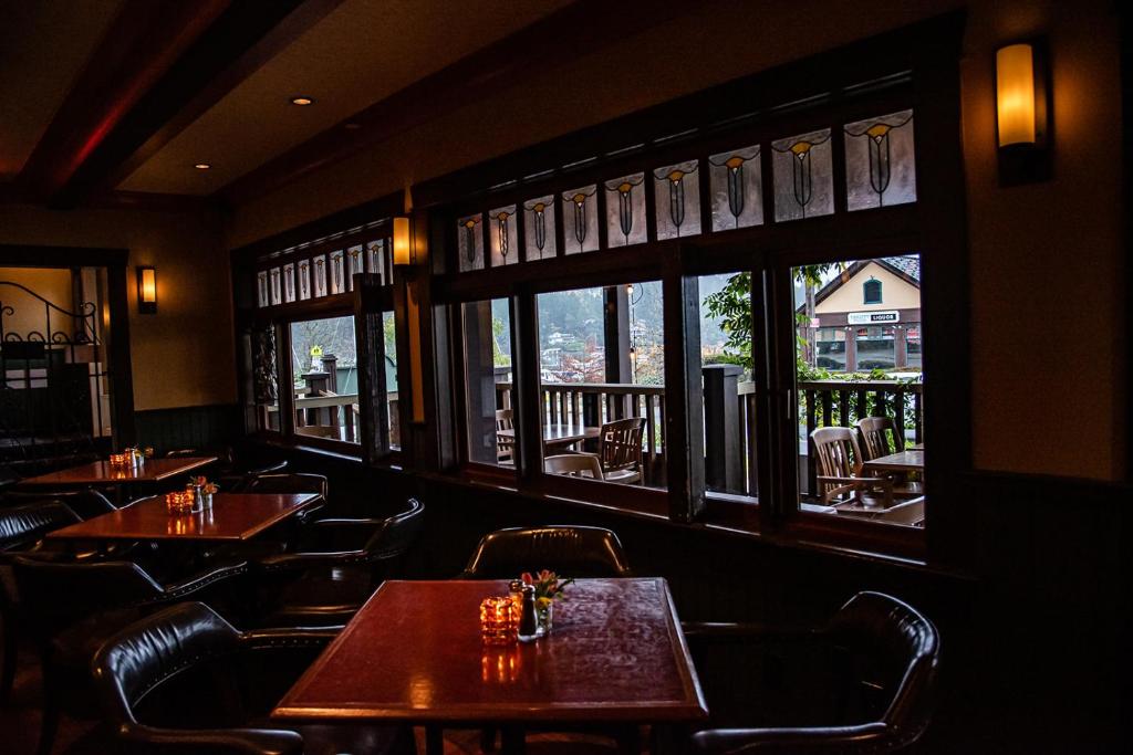 a restaurant with wooden tables and chairs and windows at Salt Spring Inn in Ganges