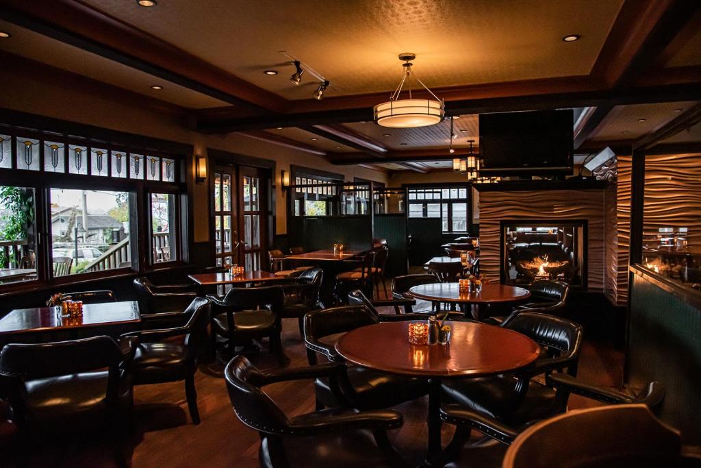 a restaurant with tables and chairs and a fireplace at Salt Spring Inn in Ganges