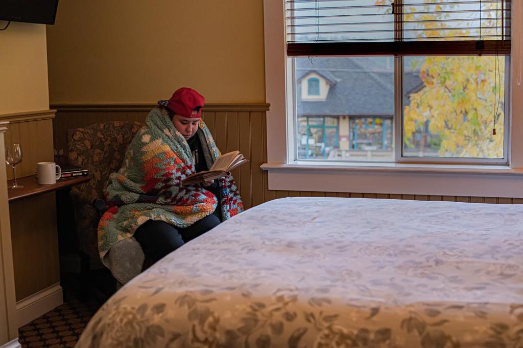 a woman sitting on a couch reading a book at Salt Spring Inn in Ganges
