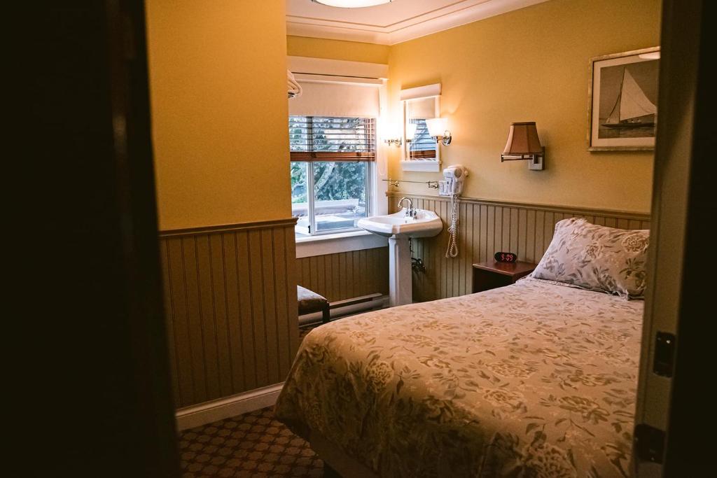 a bedroom with a bed and a sink and a window at Salt Spring Inn in Ganges