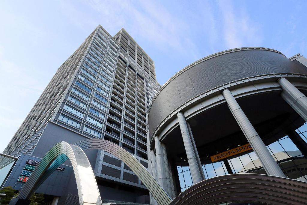 a tall building with a sculpture in front of it at Hotel Monterey Grasmere Osaka in Osaka