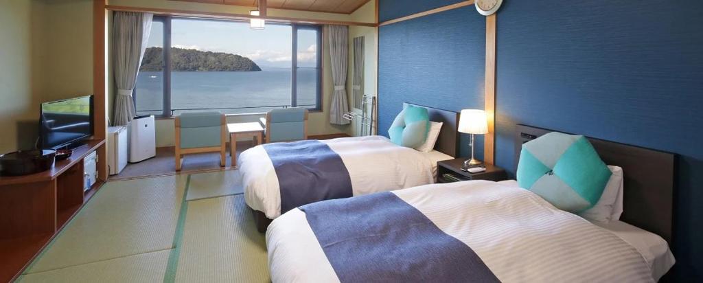 a hotel room with two beds and a view of the ocean at Kyukamura Ohmi-Hachiman in Omihachiman