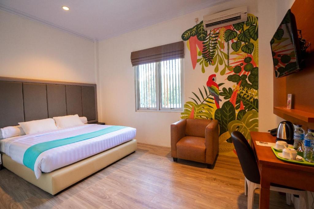 ein Schlafzimmer mit einem Bett, einem Stuhl und einem Schreibtisch in der Unterkunft Front One Green Boutique Hotel Abepura in Abepura