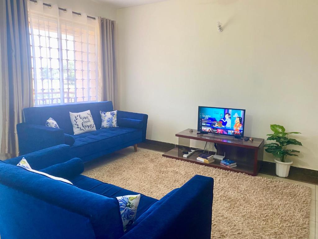 sala de estar con sofás azules y TV de pantalla plana en Dala Heights, en Mombasa