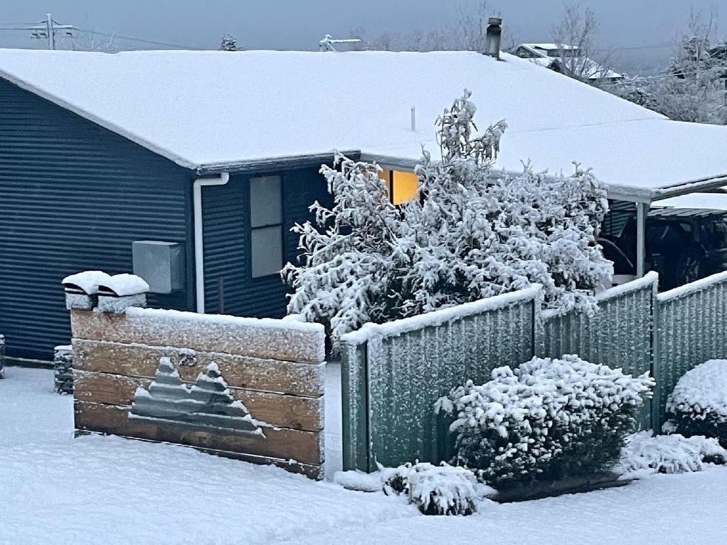 una casa con una valla cubierta de nieve en Mountain Air, en Jindabyne