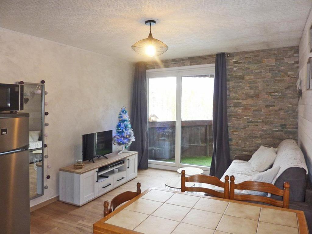 - un salon avec un arbre de Noël dans la fenêtre dans l'établissement Studio cosy 5 pers, accès direct pistes, balcon sud/ouest - FR-1-322-306, aux Orres