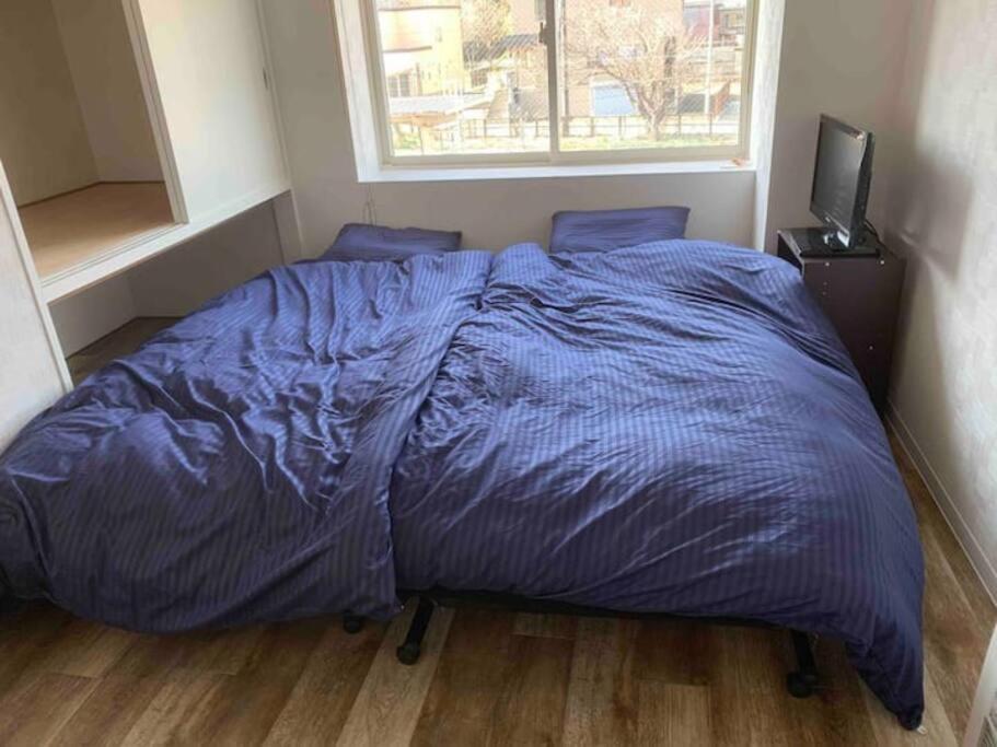 łóżko z niebieską kołdrą w sypialni w obiekcie Zenibako House 3F-RoomA w mieście Otaru