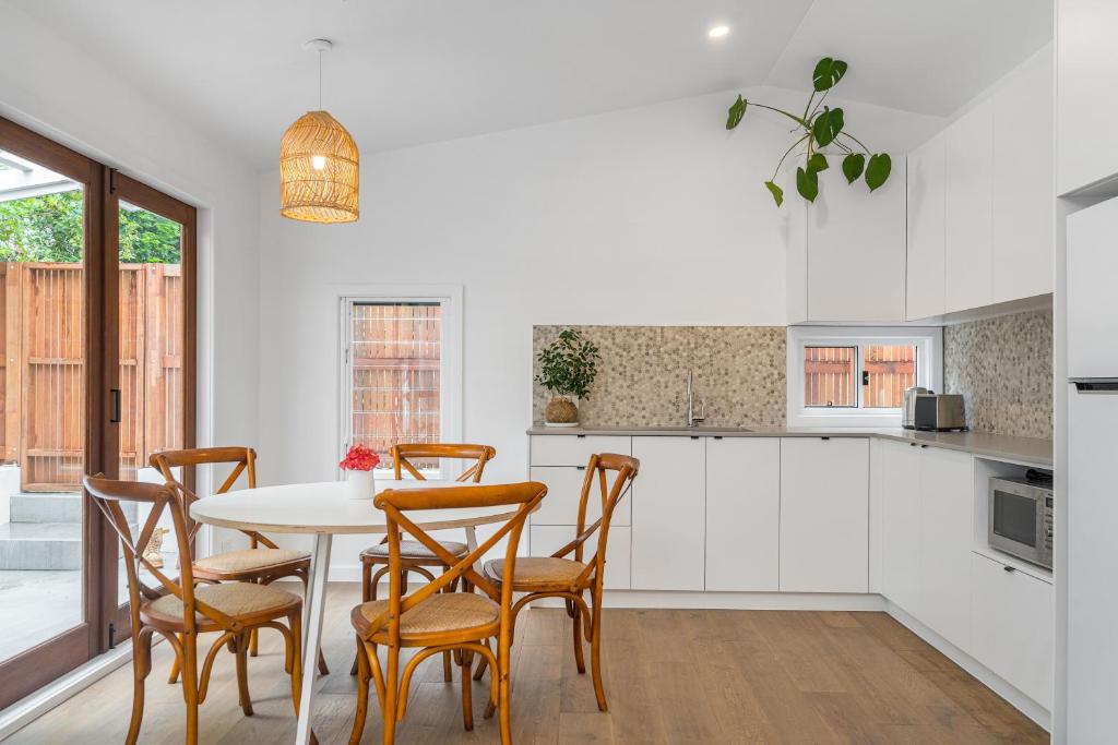 a kitchen with white cabinets and a table with chairs at Espadrille Casita in Byron Bay