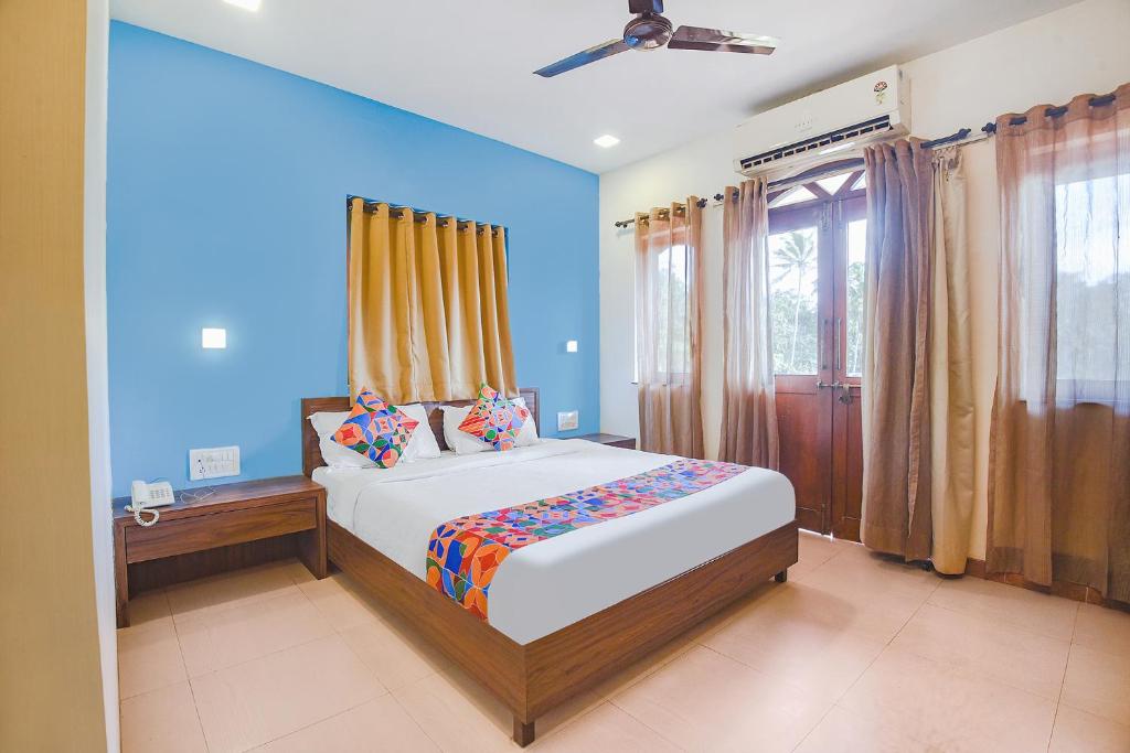 1 dormitorio con 1 cama grande y paredes azules en FabExpress Coco Goa Resort With Pool, Arpora en Saligao
