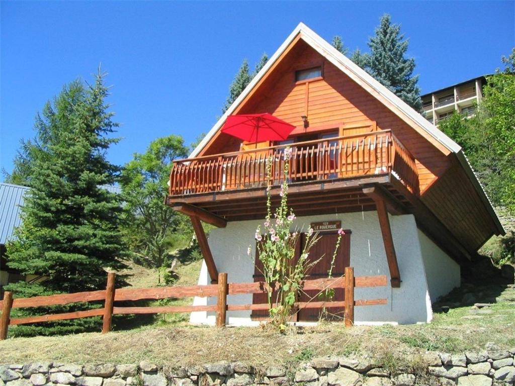a house with a balcony with a red umbrella at Chalet Saint-Michel-de-Chaillol, 3 pièces, 5 personnes - FR-1-393-13 in Saint-Michel-de-Chaillol
