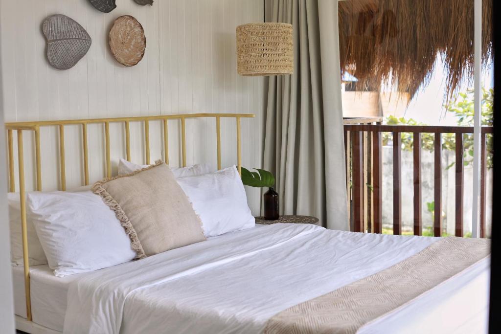 a bed with white sheets and pillows on a balcony at Sea Green Boutique Rooms in General Luna