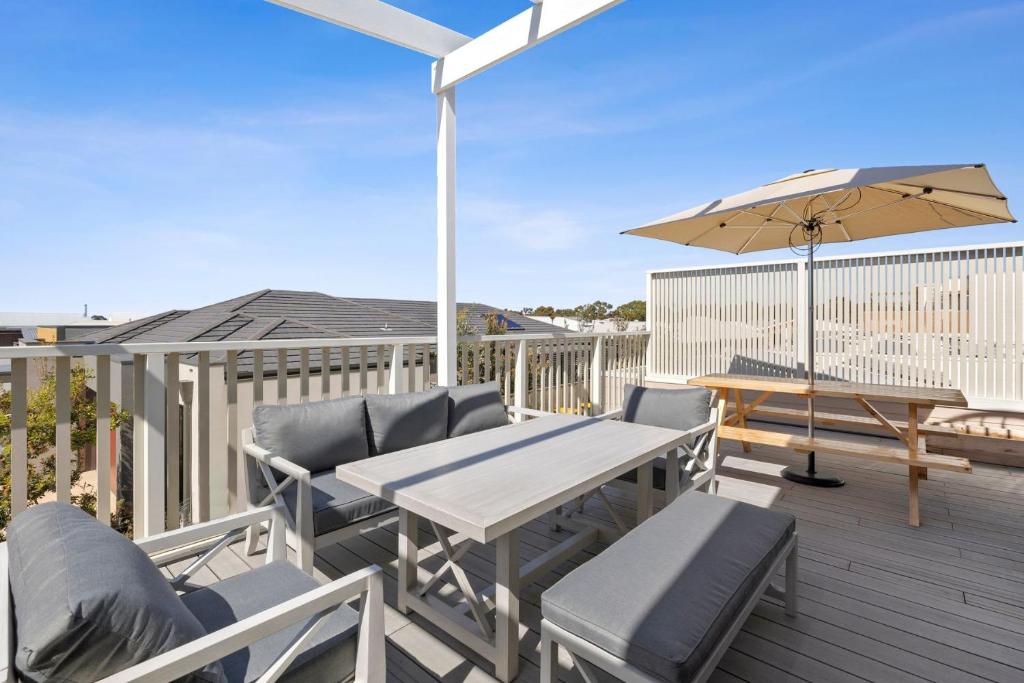 a patio with a table and chairs and an umbrella at Park View Townhouse With Rooftop Terrace in Torquay